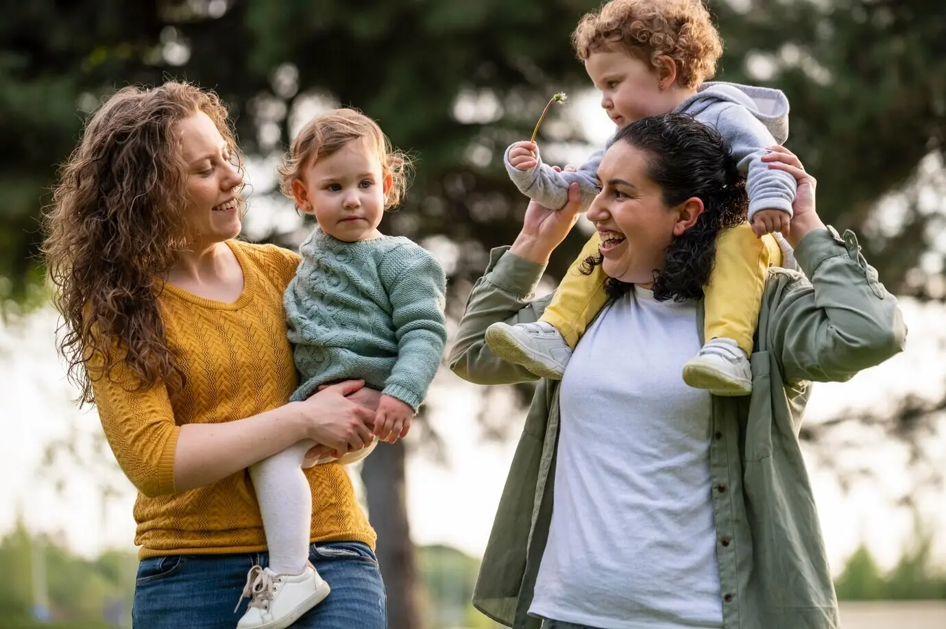 Glückliche LGBT-Mütter draußen im Park mit ihren Kindern.